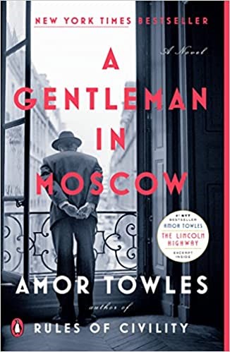 Bookcover: A Gentleman in Moscow by Amore Towles. Cover features a black and white photo taken from inside the upper level of a building of a man in a suit and hat looking over a balcony railing at the city below.