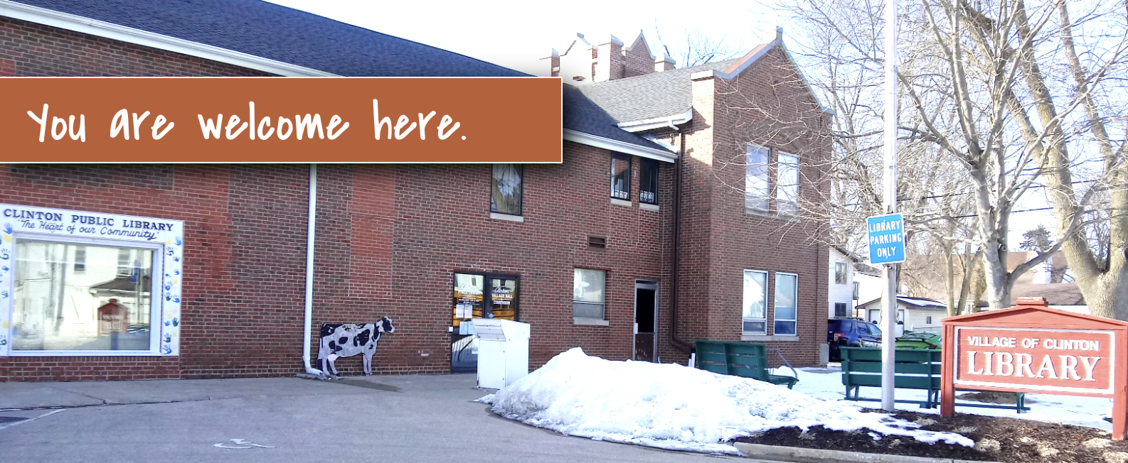 A brick building with a sign reading "Village of Clinton Library" and a banner saying "You are welcome here."