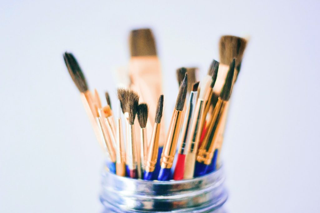 An up-close image of various sizes of paint brushes inside of a mason jar.