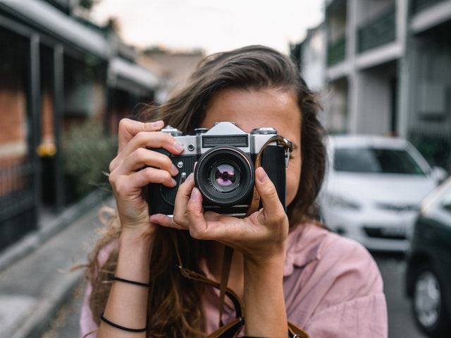 Young woman holding a camera over her face taking a picture