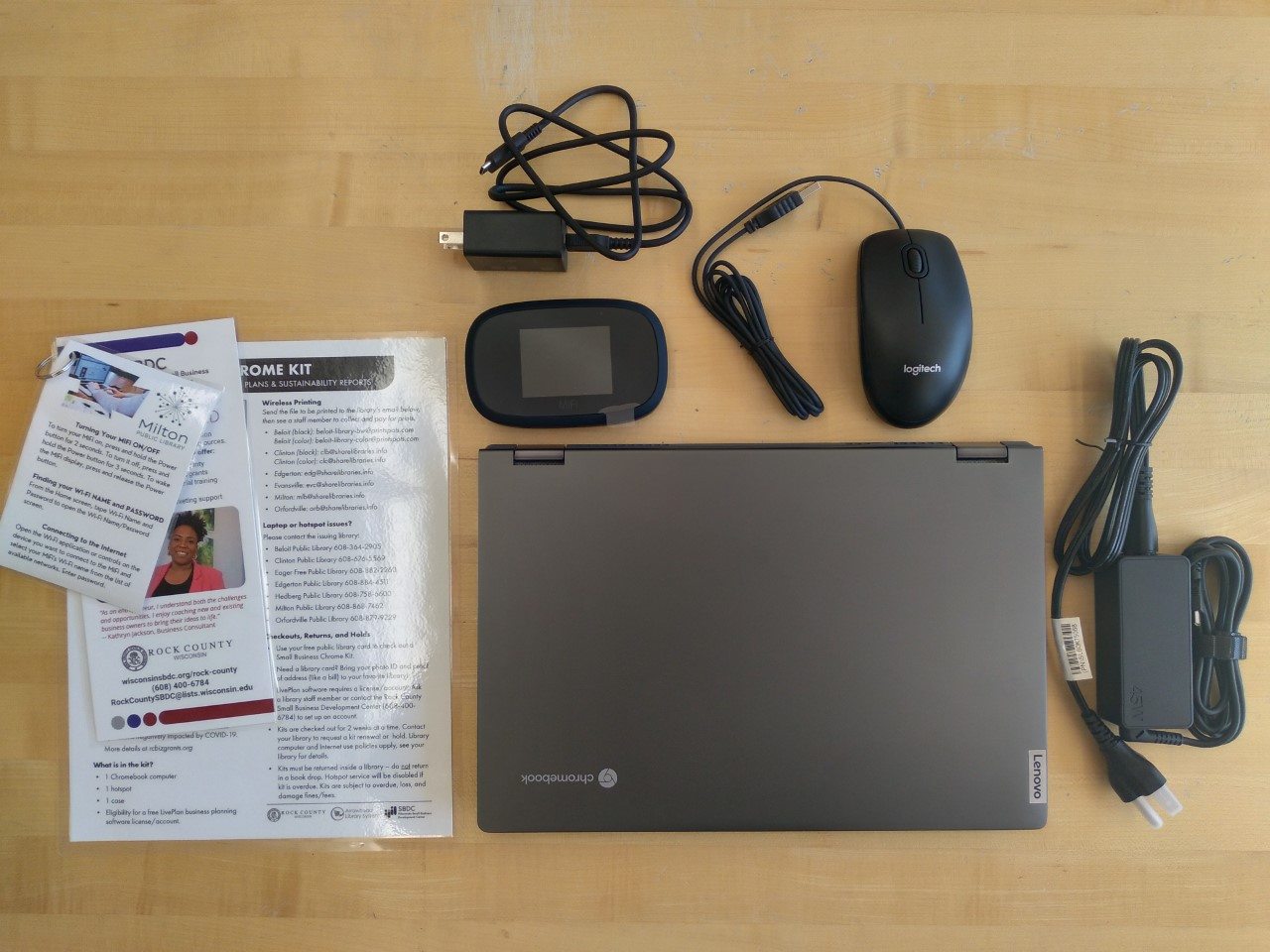 A laptop with a wifi hot spot, mouse and charger on a table.