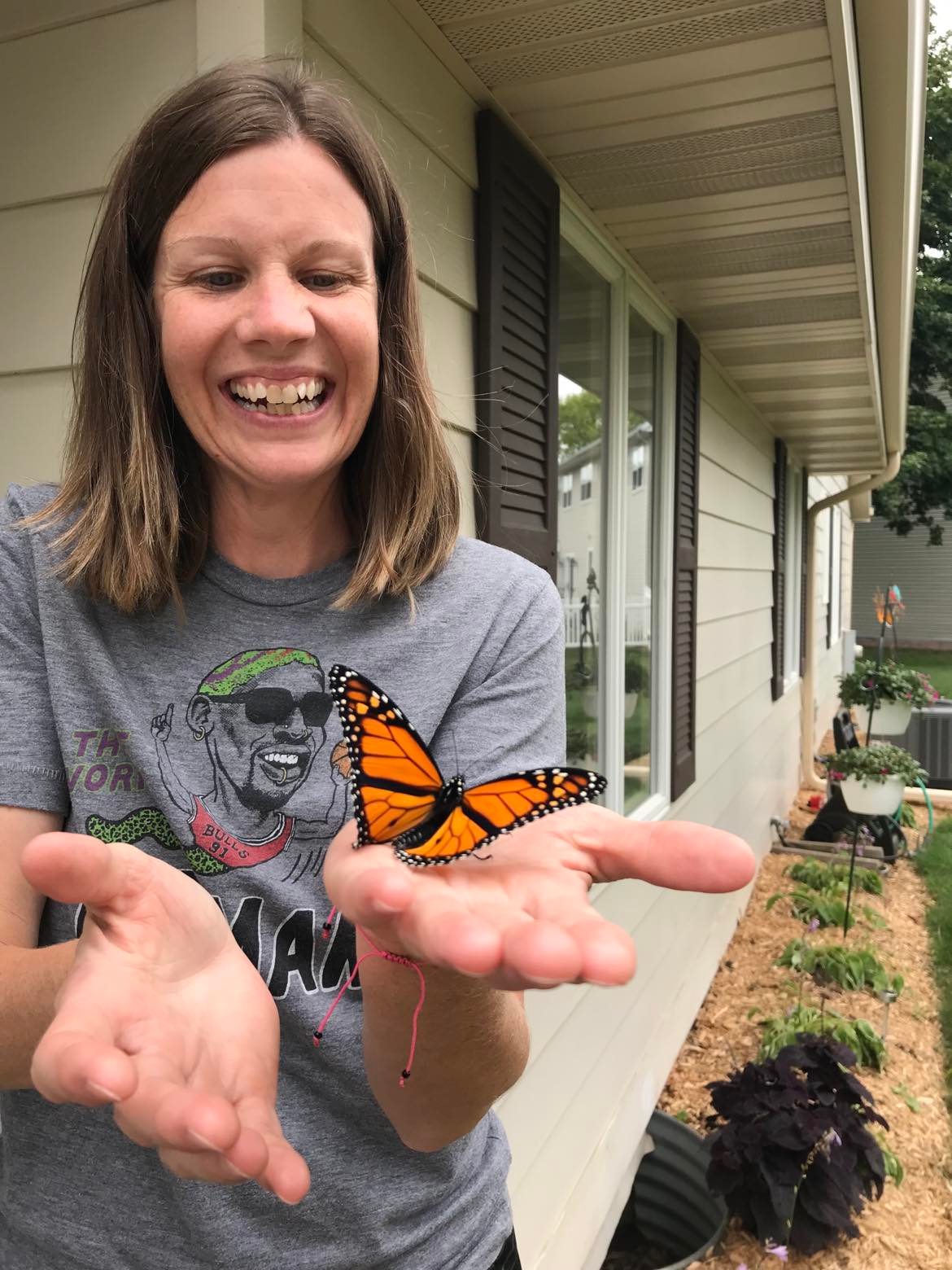 A woman with a big smile holding a monarch butterfly in her hand