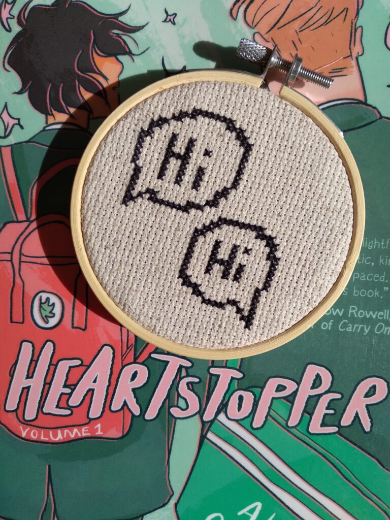 A cross stitch on top of the Heartstopper book