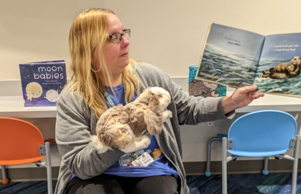 Woman reading a picture book for a story time, also holding a puppet bunny